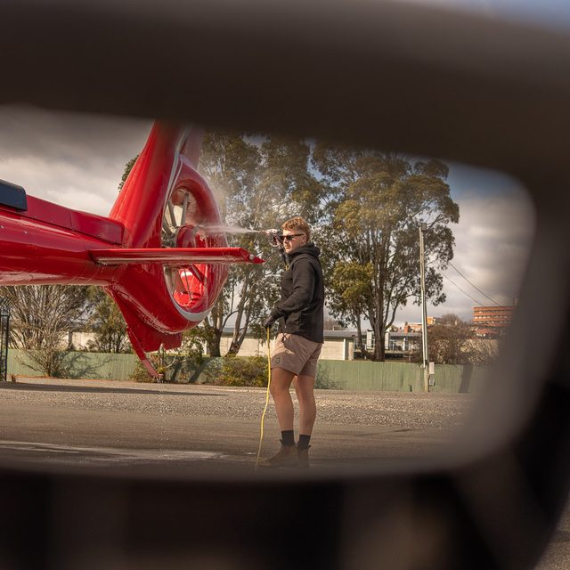 Helicopter tail being washed, framed through the detailer's equipment